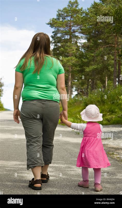 Obese Mother And Child Walking On A Forest Path On A Beautiful Summer