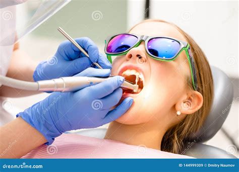 Elementary Age Girl Receiving Teeth Cleaning Procedure In Pediatric Dental Clinic Stock Image