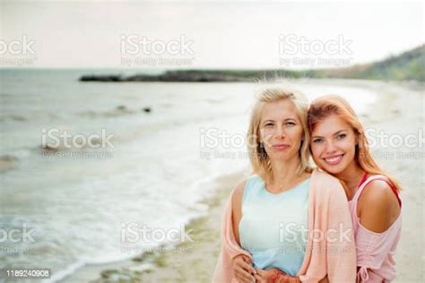 Adult Daughter Hugs Mom On The Sea Shore And Both Are Smiling Stock