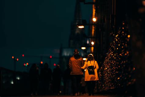 A Couple Walking On Sidewalk Of A Street During Night Time · Free Stock
