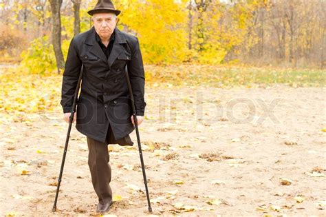 One Legged Man Walking With Crutches In The Park Stock