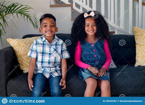 Happy African American Siblings Sitting On Sofa And Looking At Camera