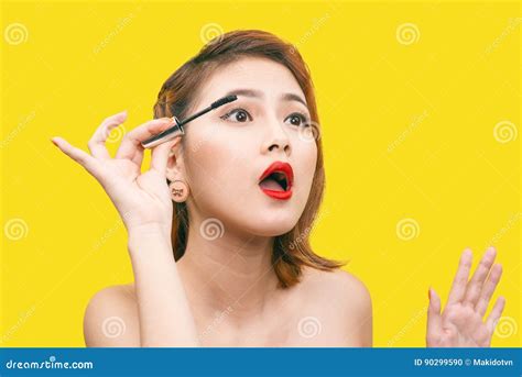 Portrait Of Asian Beautiful Woman With Makeup Brush Near Her Face Against Yellow Background