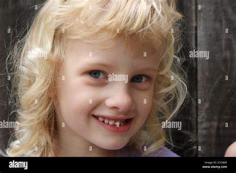 Close Up Portrait Of A Young Blonde Girl With A Mischievous Smile Stock