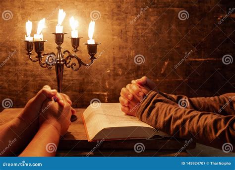 Religious Female Crossed Hands In Prayer With Bible And Candle Stock