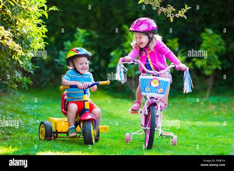 Kids Riding Bikes In A Park Children Enjoy Bike Ride In The Garden