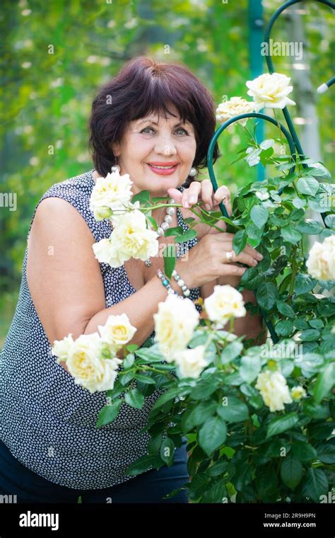 66 jährige frau im garten eine reife frau genießt die blumen einer rose die mit ihren eigenen