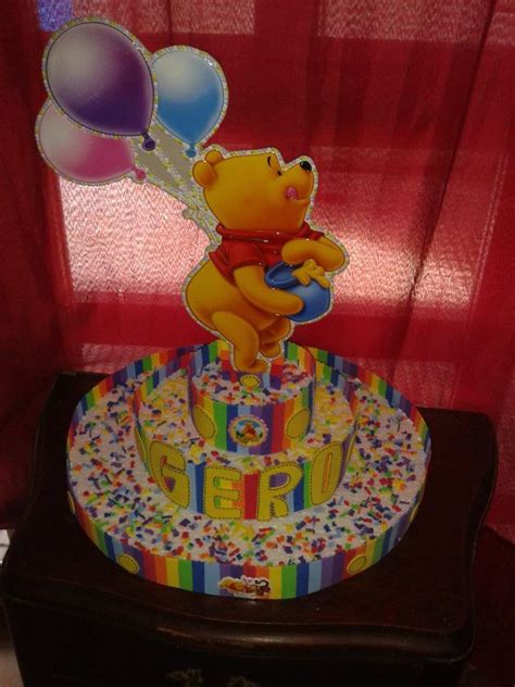 A Winnie The Pooh Birthday Cake With Balloons And Streamers In Front Of