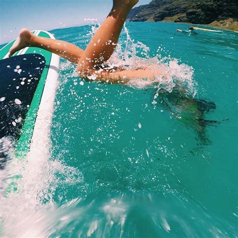 A Woman Laying On Top Of A Surfboard In The Ocean