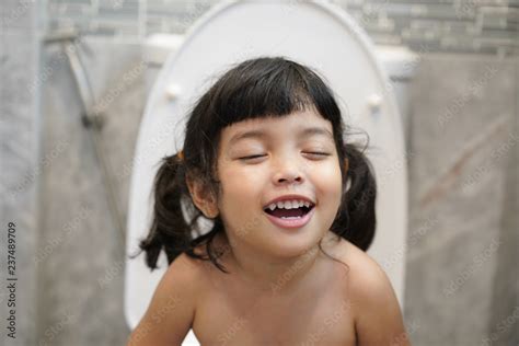 Cute Asian Little Girl In Restroom Happy Kid Sitting On The Toilet