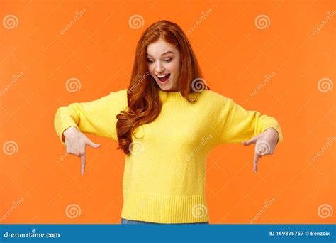 Wondered And Excited Amused Cute Redhead Woman In Yellow Sweater Pointing Fingers Down Look