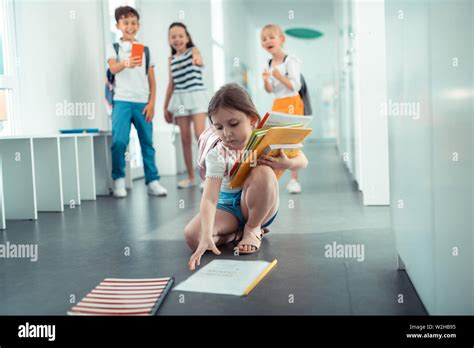 Girl Picking Up Books From Floor After Babe Pushed Her Stock Photo Alamy