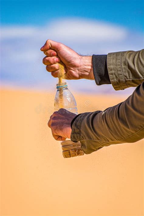 Man Pouring Sand To The Bottle In Desert With Sandstone And Granite