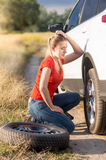 Premium Photo Woman Sitting At Broken Car And Trying To Change Flat Tire