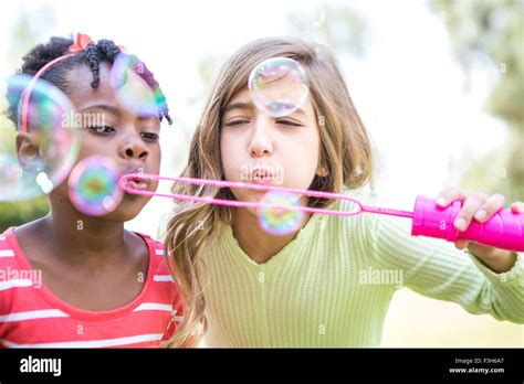 Girls Blowing Bubbles In Park Stock Photo Alamy
