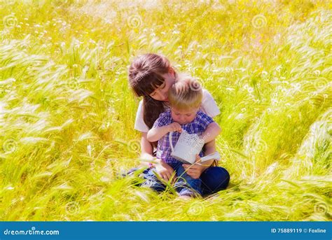 Little Boy And Girl In The Summer Field With Flowers Stock Image