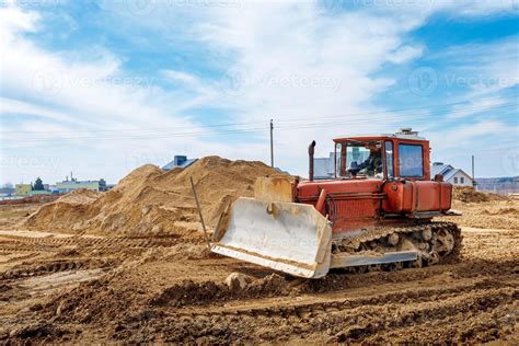 An Old Orange Bulldozer Performs Work To Level The Sandy Soil 22808945