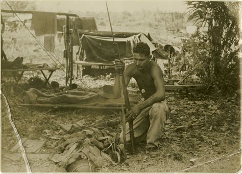 australian soldier kneeling next to body of a dead japanese soldier on labuan island near