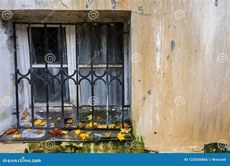 Old Dirty Window With Metal Grid On Building Wall With Fallen Colorful