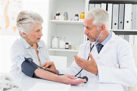 Doctor Taking The Blood Pressure Of His Retired Patient Stock Image