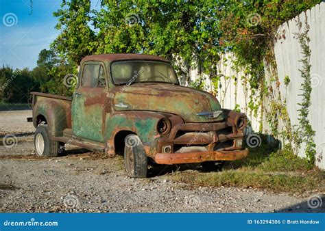 rusted vintage chevrolet pickup truck parked by a white fence editorial photo image of