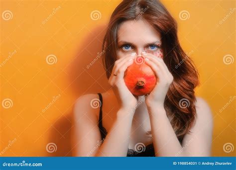Female Portrait And Red Fruit Girl With A Pomegranate On An Orange Background Stock Image