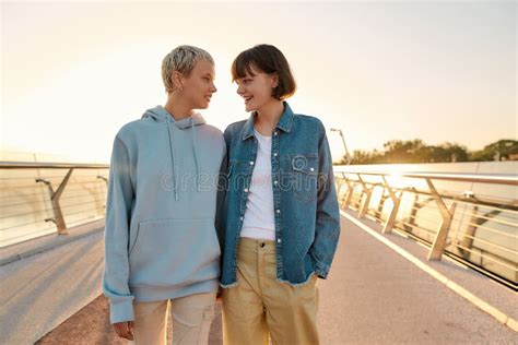 Happy Lesbian Couple Laughing Having Fun Holding Their Hands While Walking On The Bridge And