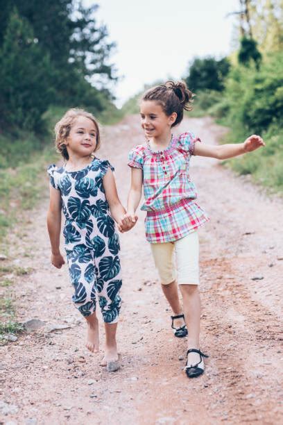 60 Two Sisters Walking On Path Holding Hands Smiling Stock Photos