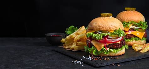 Two Burgers French Fries And Juice On A Black Background Stock Photo