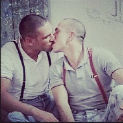 Two Men Are Kissing Each Other While Sitting On The Floor In Front Of A
