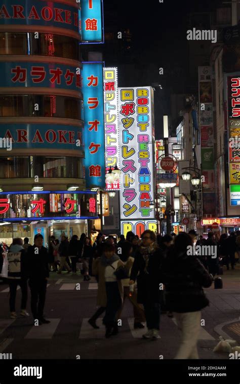 crowds enjoying the night life under the neon lights of the tokyo red light area in shinjuku