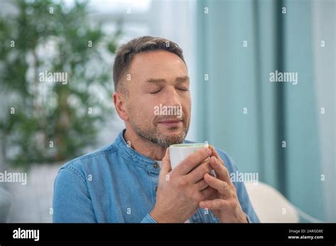 Cute Man With A Cup In His Hands Closing His Eyes Stock Photo Alamy