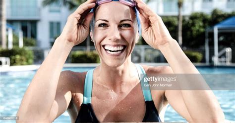 Portrait Of Smiling Female Swimmer Leaning On Edge Of Swimming Pool