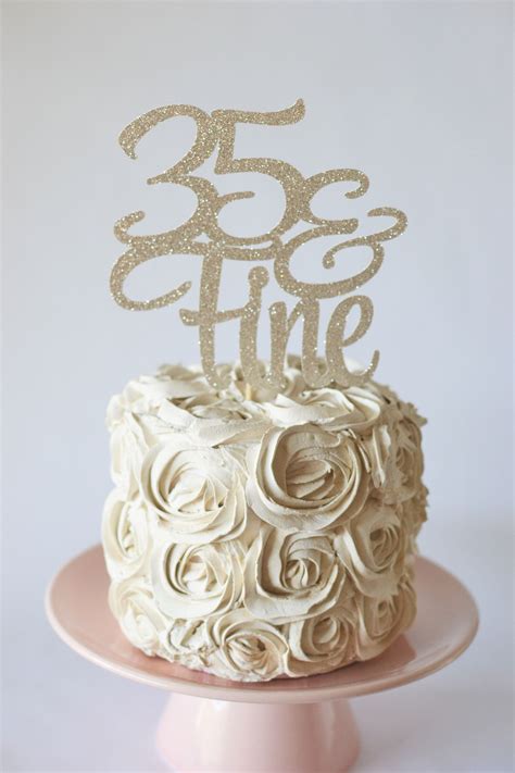 A White Cake With Gold Frosting And The Number 350 On Top Is Sitting On