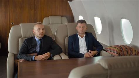 Young Businessmen Talk Sit In Airplane Interior During Flight Stock