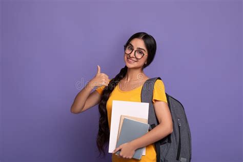 Happy Indian Student Wearing Eyeglasses Holding Notebooks Showing