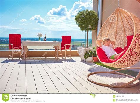 Young Boy Relaxing In Hammock On Modern Rooftop Patio