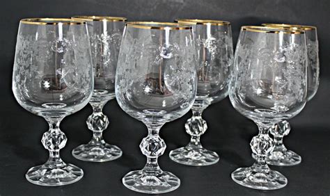 four wine glasses with gold rims are lined up on a black tableclothed surface