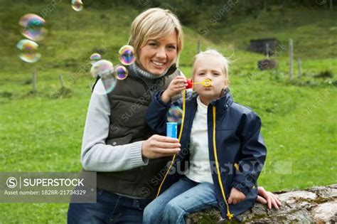 Mother And Daughter Blowing Bubbles Superstock