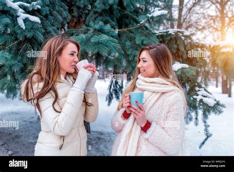 Two Girls Girlfriends In Winter Background Green Firs In Snow Happy
