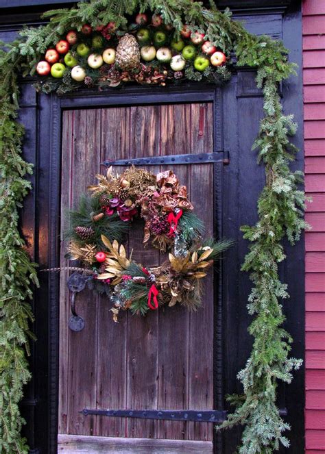 A pair of festive christmas evergreen wreaths adorn a set of large wooden doors, serving as decorations during the holiday beautiful christmas wreath home decorations lights on front door of house. 50 Best Christmas Door Decorations for 2017