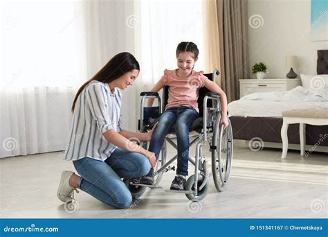 Young Woman Helping Her Disabled Daughter Get In Wheelchair Stock Image