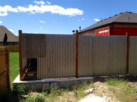 Using wide horizontal panels of corrugated metal, this fence relies on the dark wooden posts to stand strong. corrugated metal fence update - noelle o designs