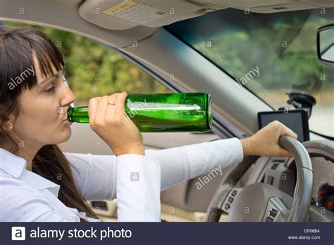 Drunk Female Driver In Her Car Driving Along The Road Gulping Booze