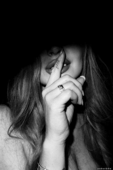 a black and white photo of a woman holding her finger up to her mouth while wearing a ring