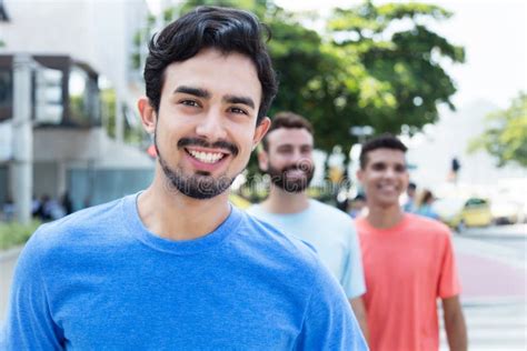 Laughing Hispanic Guy Walking With Two Friends In The City Stock Photo