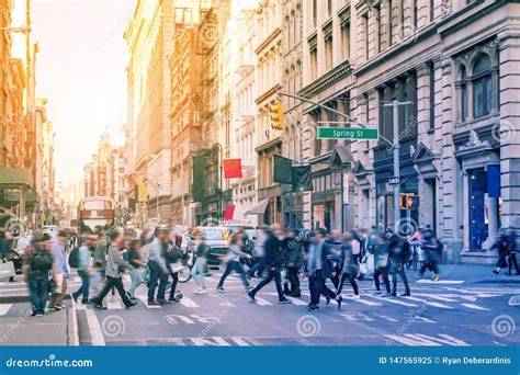 Diverse Groups Of People Walk Across The Crowded Intersection Of