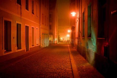 Dark Urban Alley With Illuminated Street Lights At Night Stock Photo