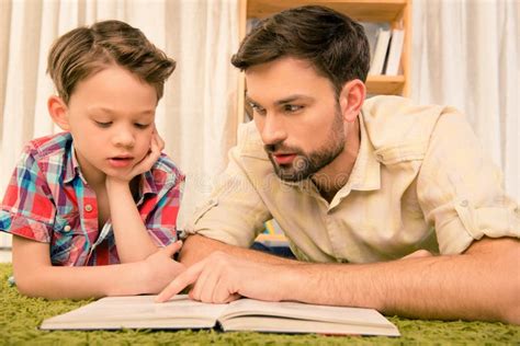 Close Up Portrait Of Father Teaching His Son To Read Book Stock Photo