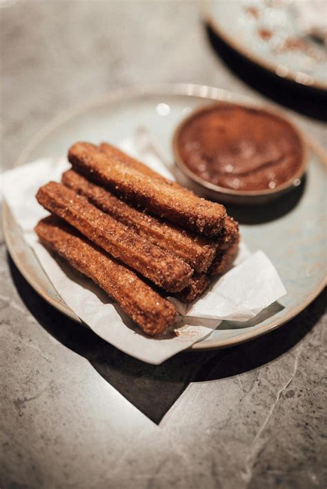 Delicious Churros With Chocolate Sauce Served On Plate In Cafe · Free